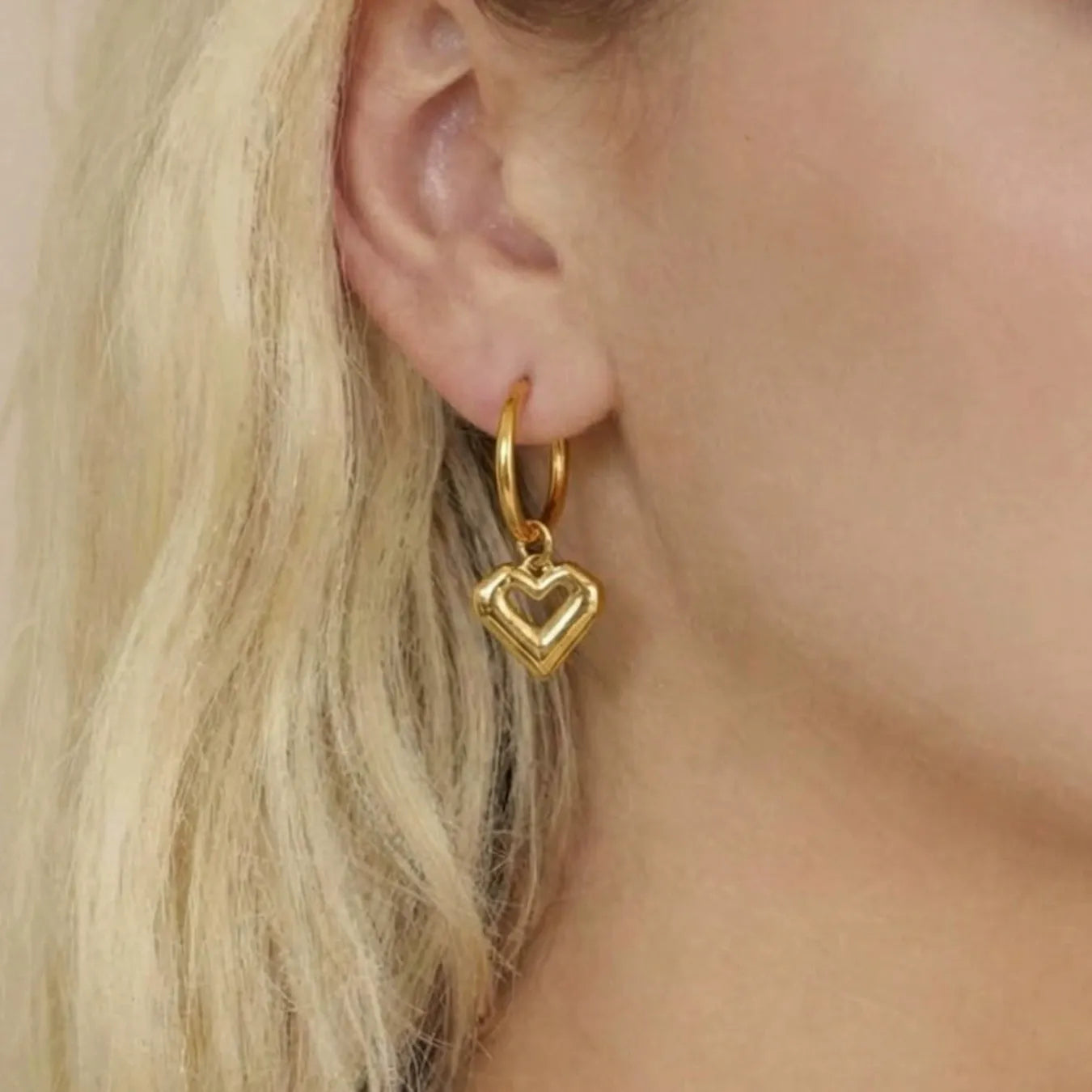 Model showcasing everyday wear dainty heart dangle hypoallergenic earrings in 18K gold stainless steel.