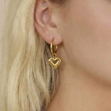 Model showcasing everyday wear dainty heart dangle hypoallergenic earrings in 18K gold stainless steel.