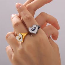 Model wearing gold-tone and steel-tone evil eye heart rings on the fingers in a close-up hand shot