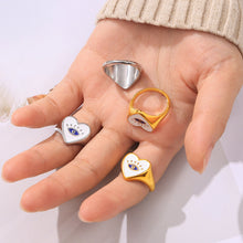 Close-up of a model wearing multiple evil eye heart rings in gold-tone and steel-tone finishes