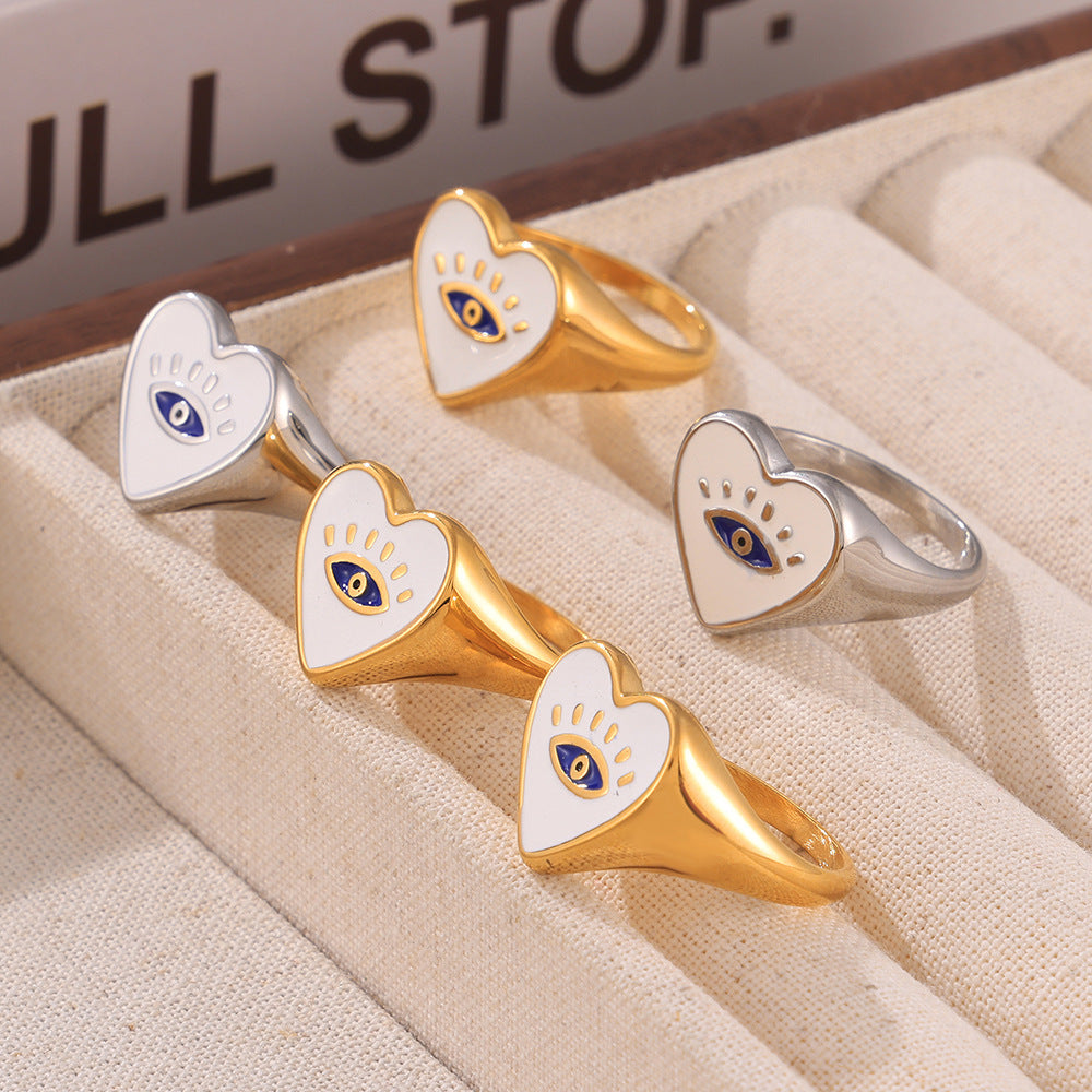 Gold-tone and steel-tone evil eye heart rings arranged in a flat lay jewelry display
