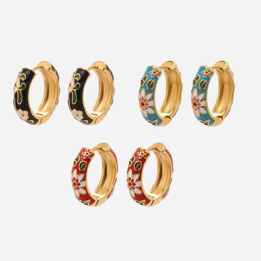 Flatlay of stainless steel enamel floral hoop earrings in three colors: black, blue, and red.