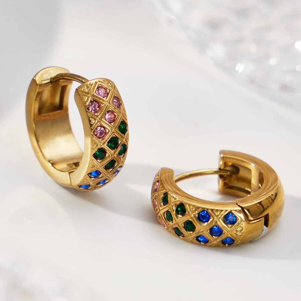 Gold-tone multicolor CZ lattice hoop earrings with one hinged clasp open.