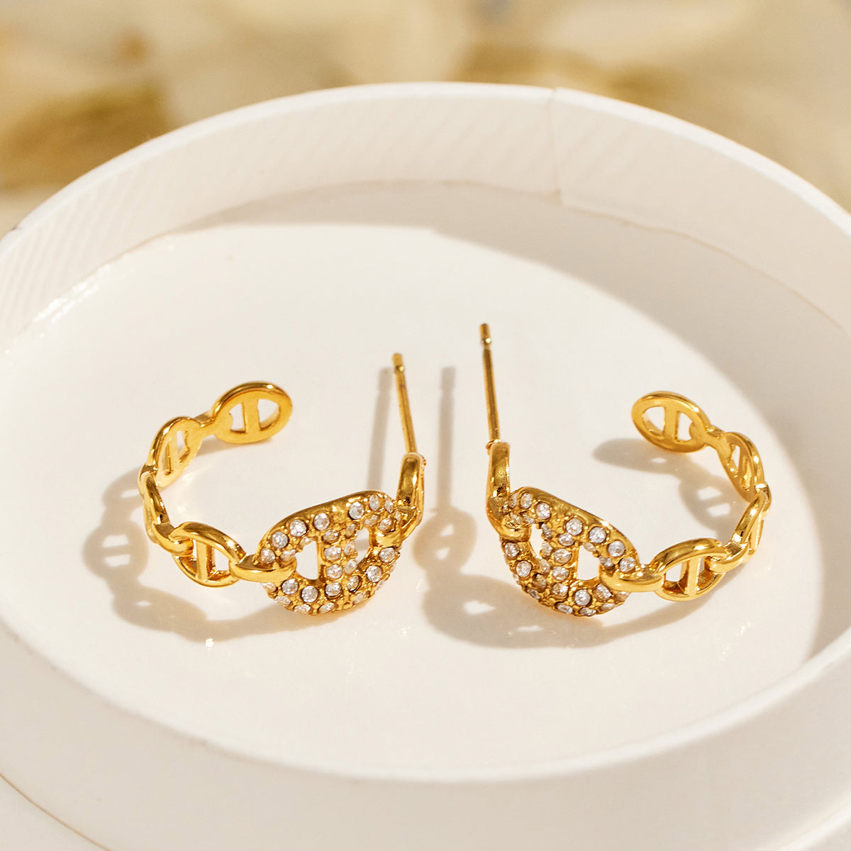 Pair of gold geometric hoop earrings with pavé zircon C-shaped tops and polished chain link drops