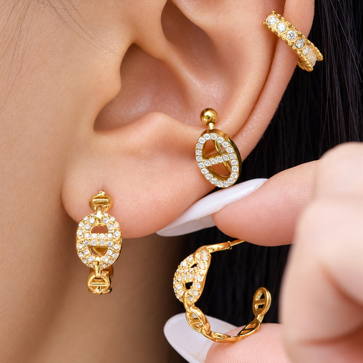 Hand-held pavé chain hoop earrings showing zircon-set C-shaped hoops and polished gold link construction