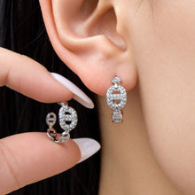 Model wearing silver-tone chain link hoop earrings with clear zircon pavé details and geometric links