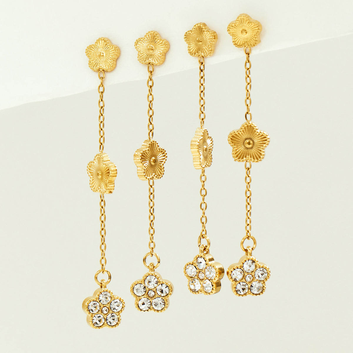 Multiple gold flower drop earrings displayed together for a coordinated boutique and wholesale jewelry assortment