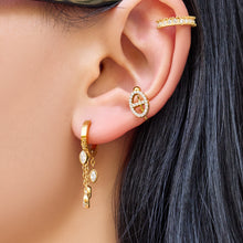 Gold chain-drop hoop earrings worn on the ear with three moving marquise zircon details