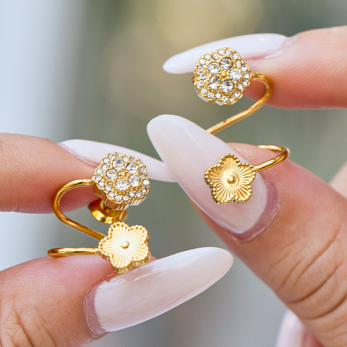 Hand-held gold flower ear cuff showing zircon pavé detail, floral motif and smooth spiral cuff shape