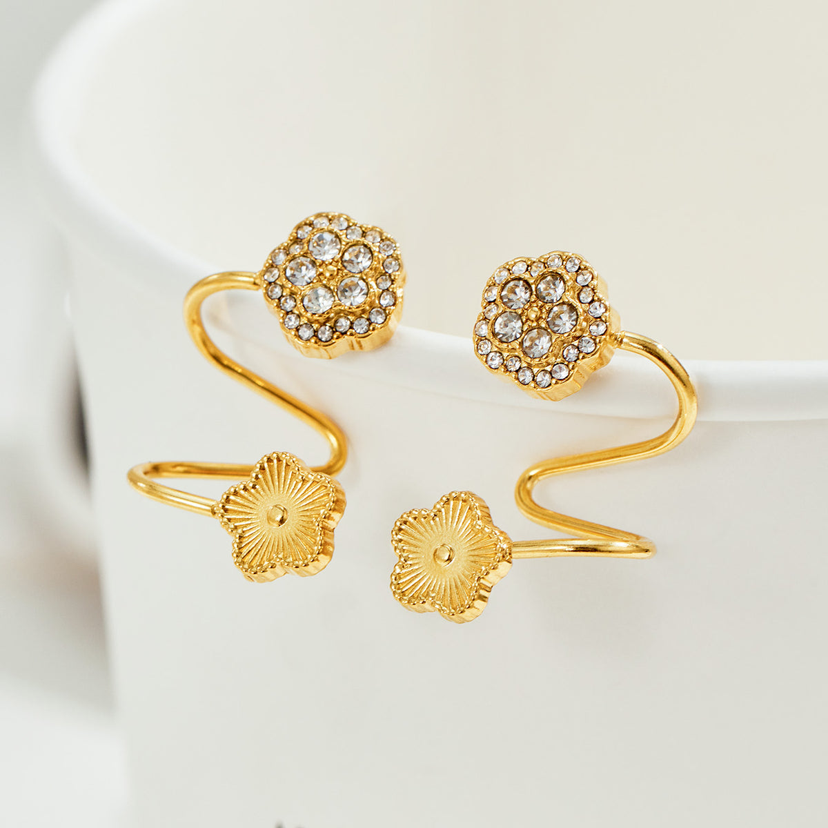 Pair of gold flower ear cuffs with zircon-set round floral tops and polished flower end details