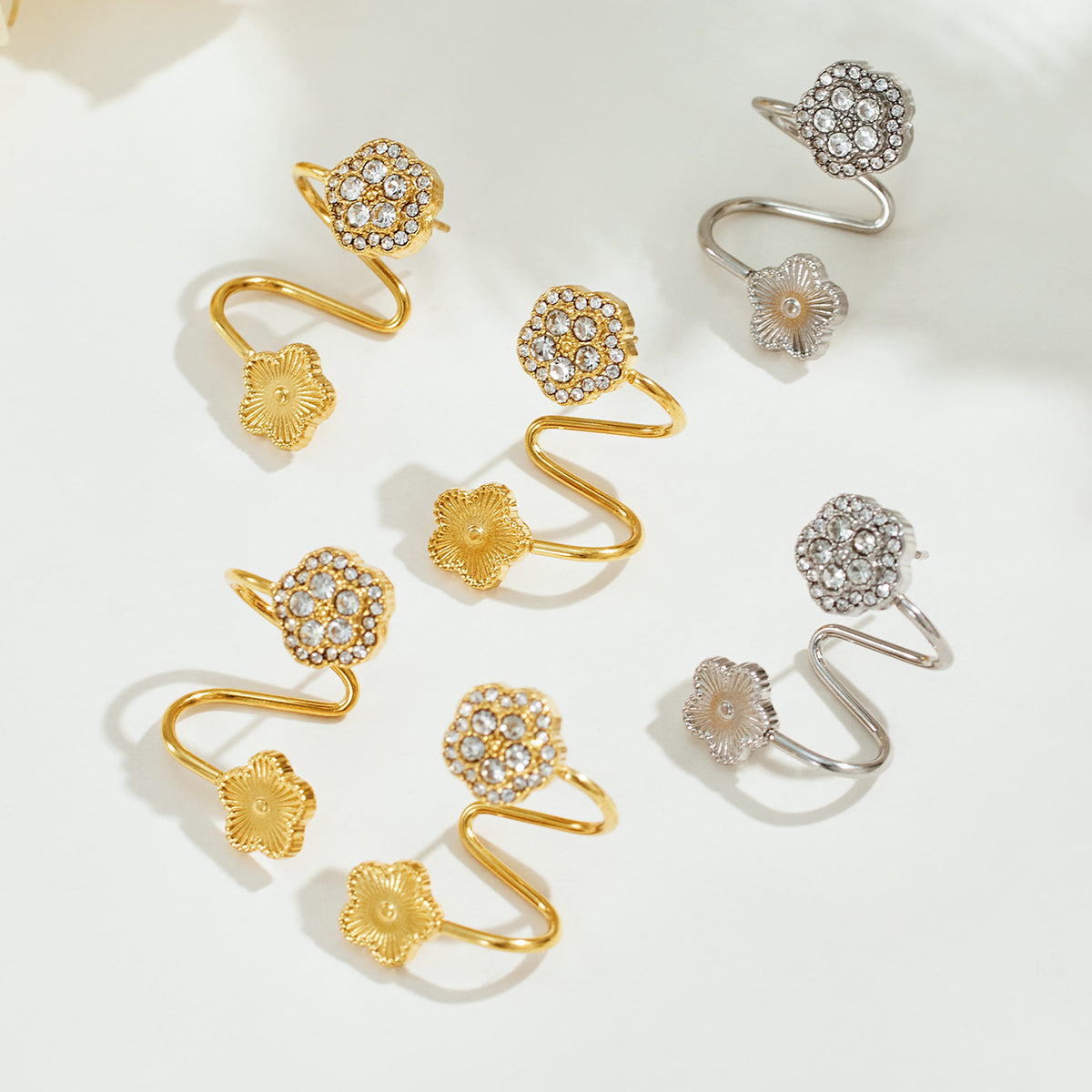 Gold and silver flower ear cuffs displayed together with zircon-set floral tops and non-pierced designs