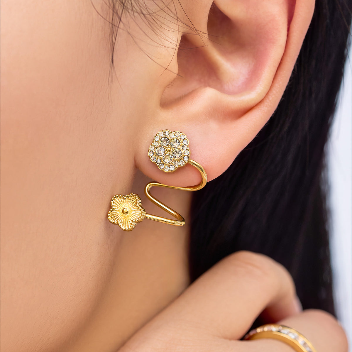 Close-up of gold zircon flower ear cuff worn on the ear with a delicate double-flower design