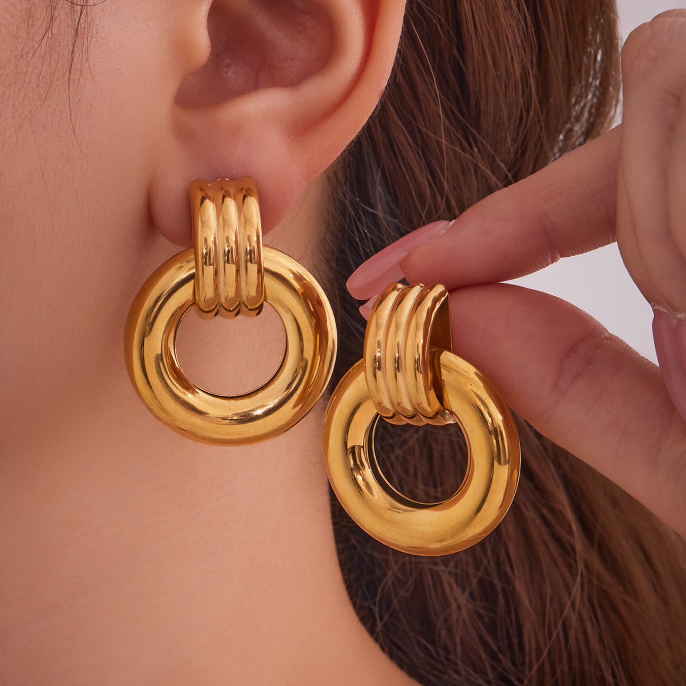 Gold-tone F476 round stainless steel door knocker earrings shown on model