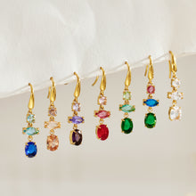 Seven colorful gold fishhook drop earring designs hanging in a row, showing their different faceted stone combinations