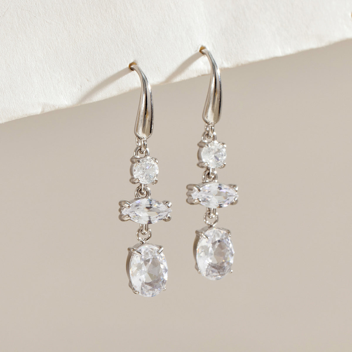 Pair of silver-tone stainless steel drop earrings featuring clear round, marquise-shaped and oval stone accents