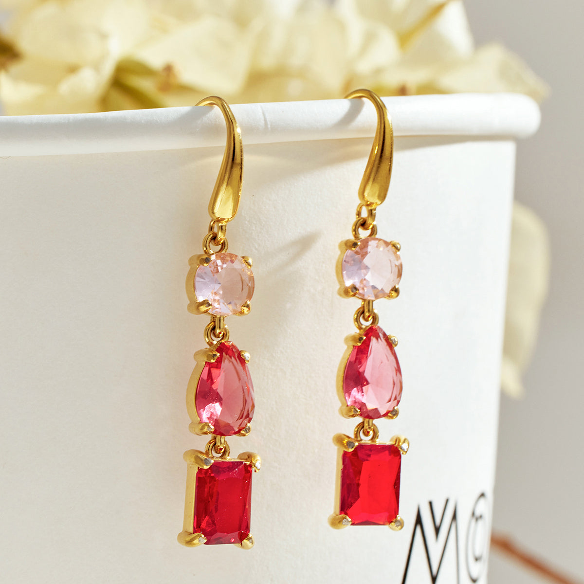 Pair of gold drop earrings with pale pink top stones, pink pear-shaped centers and red rectangular bottom stones