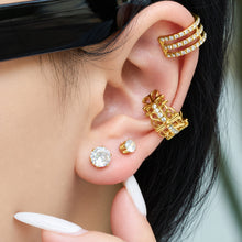 Model wearing sparkling round solitaire stud earrings alongside gold ear accessories, with a hand near the ear