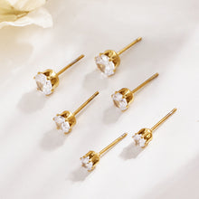 Gold-tone round stone stud earrings arranged on a light surface, showing their straight posts and prong settings