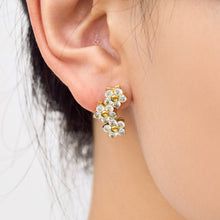 Gold flower cluster drop earring worn on the earlobe, highlighting the cascading arrangement of three five-petal flowers