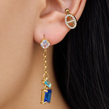Side-profile model wearing blue zircon drop earrings with linked gold-tone chain and baguette stone