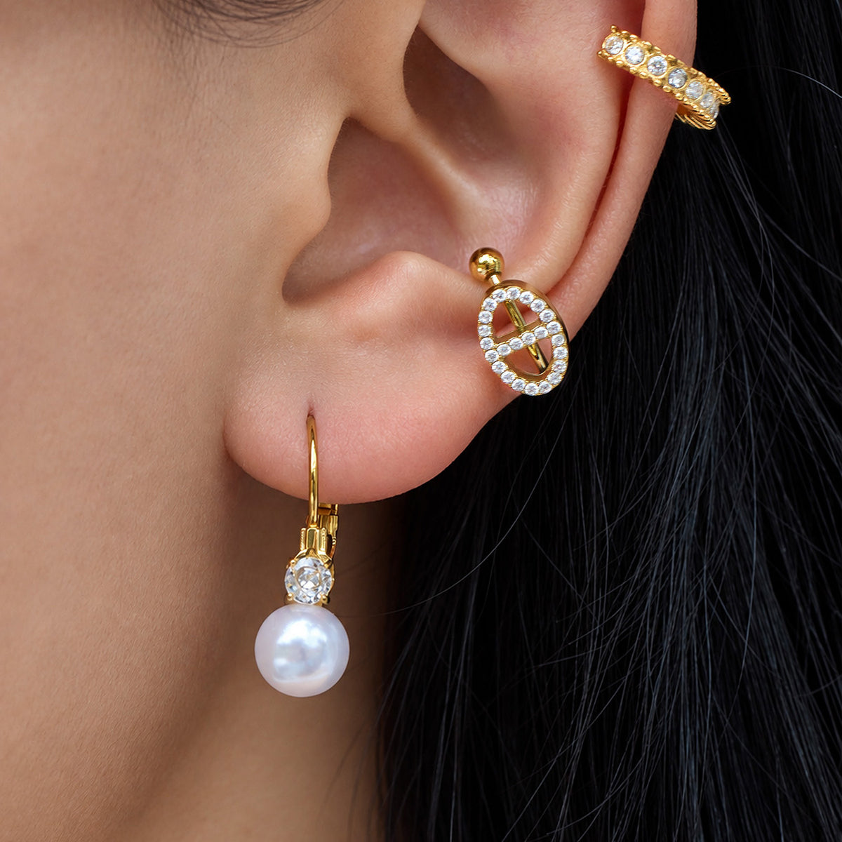 Model wearing a gold shell pearl drop earring with a round white pearl and sparkling clear stone accent