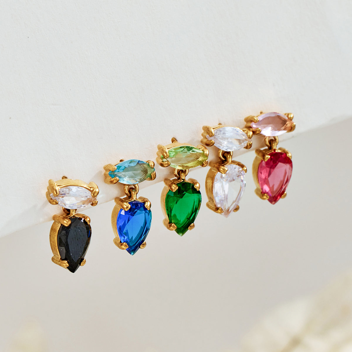 Five-color zircon drop earring assortment in black, blue, green, clear and red arranged for boutique jewelry selection