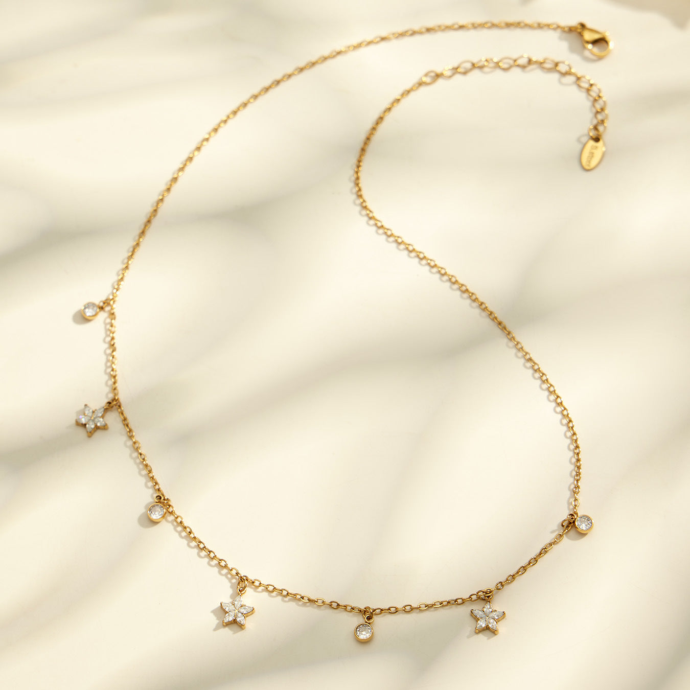 Flower zircon charm necklace flatlay with delicate 18K PVD gold chain and stainless steel finish