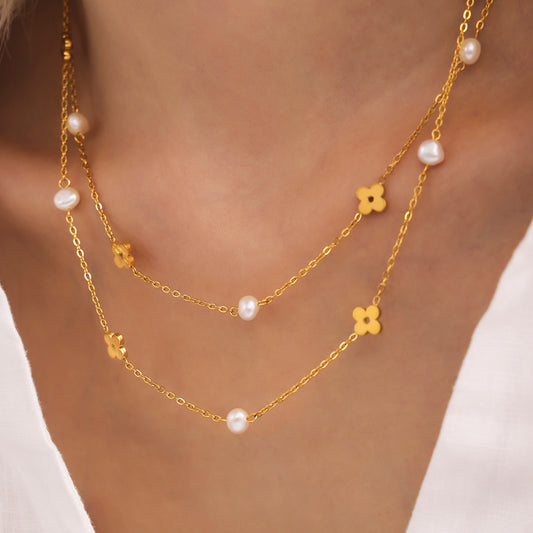 Model wearing a delicate gold freshwater pearl clover necklace with spaced floral motifs
