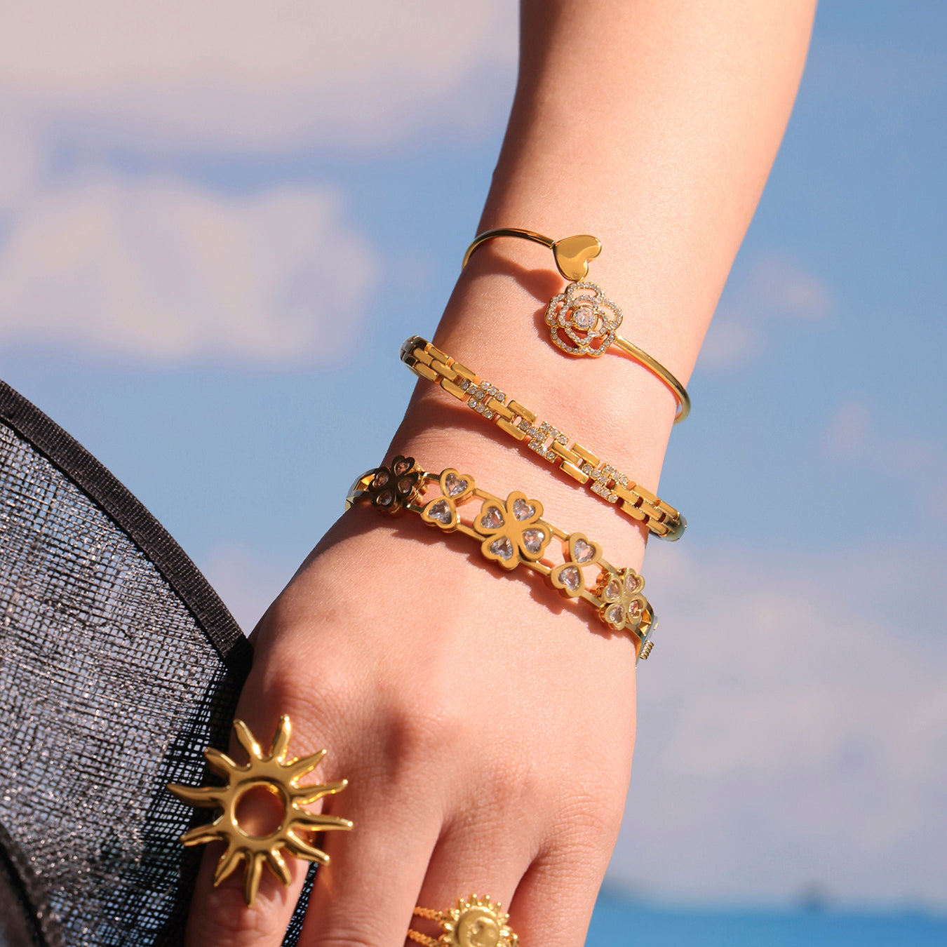 Woman wearing 5A zircon full diamond heart rose thin open bangle, layered with other gold jewelry