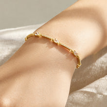 Delicate gold zircon bracelet with geometric stone details worn on the wrist