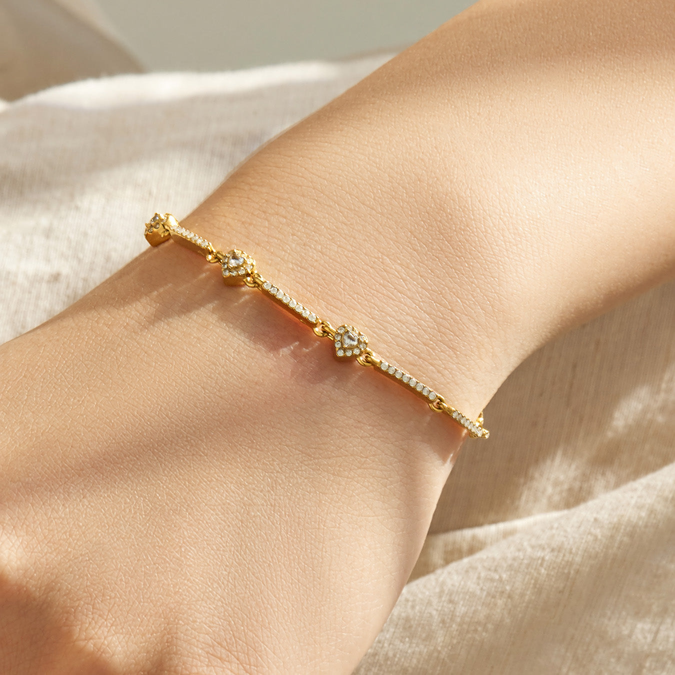 Gold geometric zircon bracelet with sparkling center detail shown in a close-up wrist view