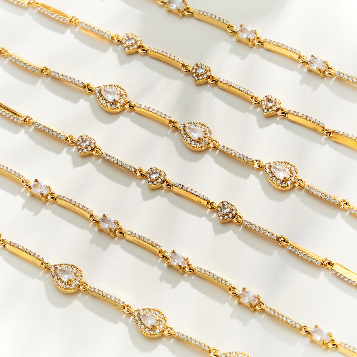 Gold zircon bracelets arranged in rows showing repeating stone details and delicate chain construction