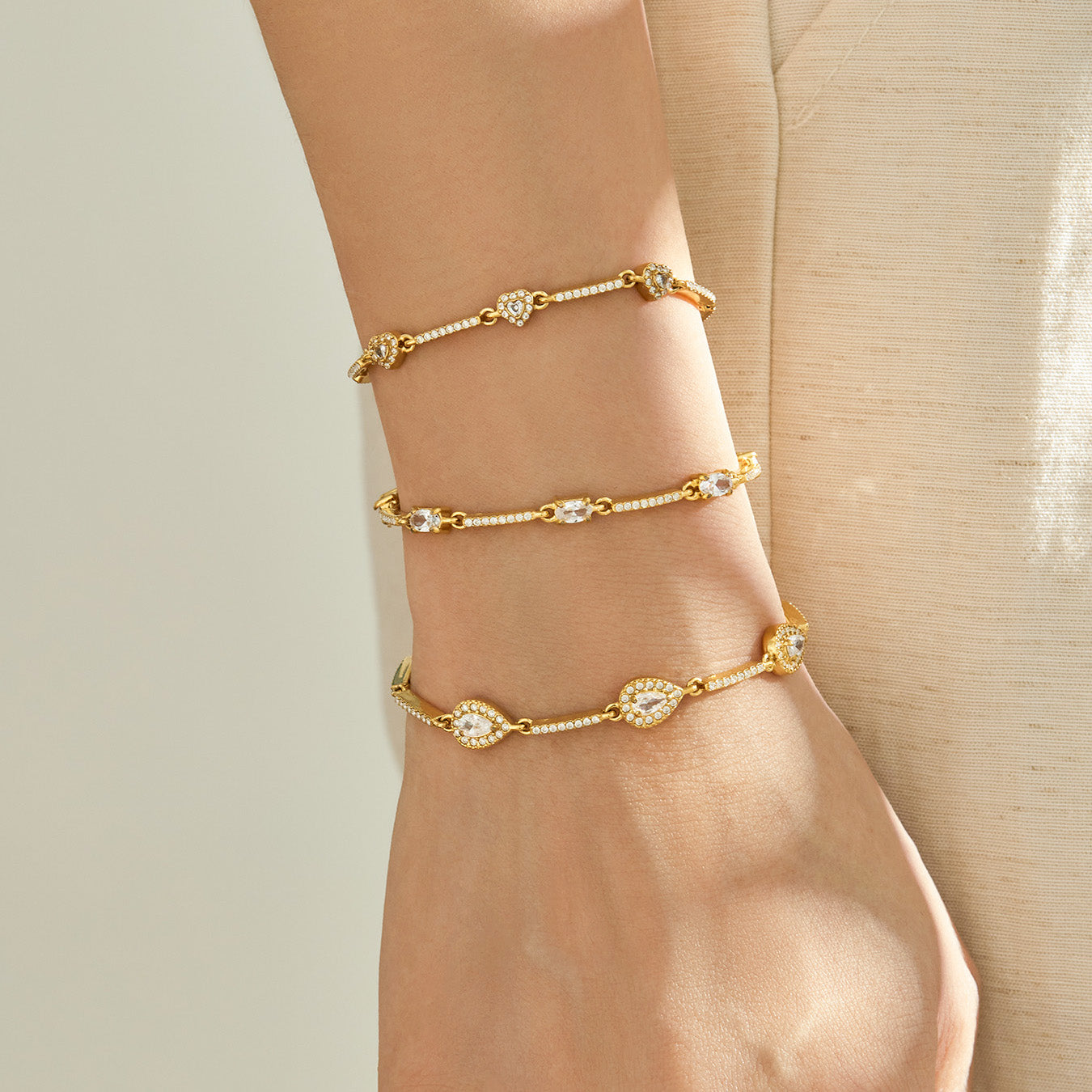 Three geometric zircon bracelet designs layered vertically on a model wrist