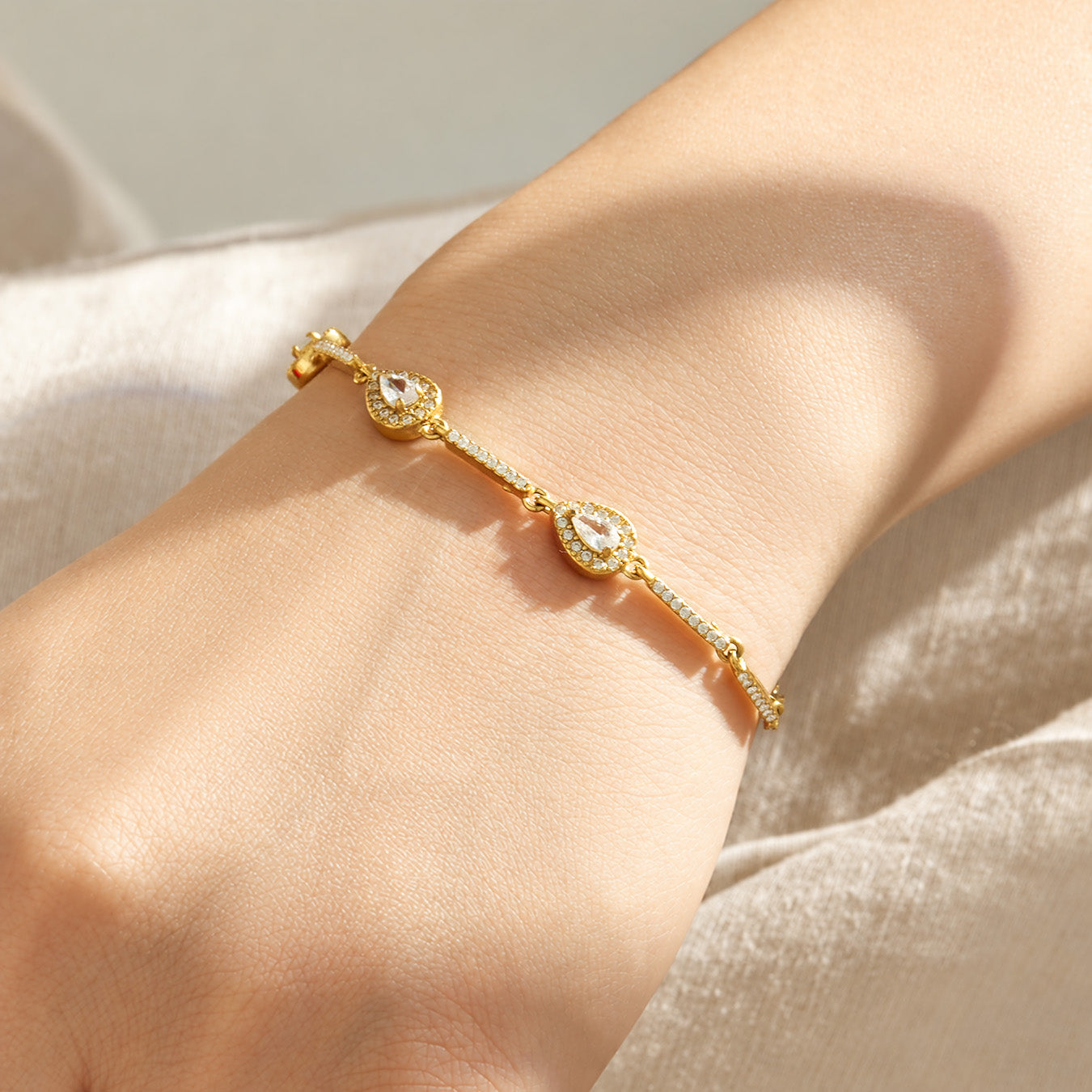 Two delicate gold zircon bracelets layered on the wrist with sparkling geometric details