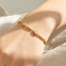 Two delicate gold zircon bracelets layered on the wrist with sparkling geometric details