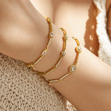 Three delicate gold zircon bracelets with geometric center details worn together on the wrist