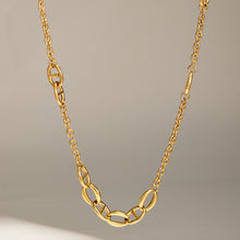 Gold geometric chain necklace showing mixed oval link details on a neutral display