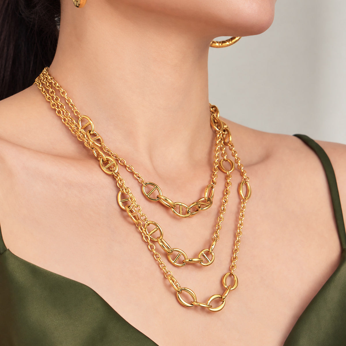 Geometric oval link necklace layered with gold chains on model