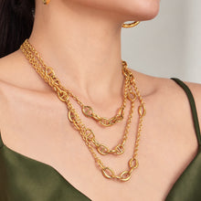 Geometric oval link necklace layered with gold chains on model