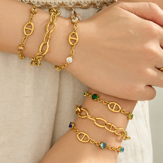 Gold oval link bracelets layered on both wrists with plain and zircon-accented styles