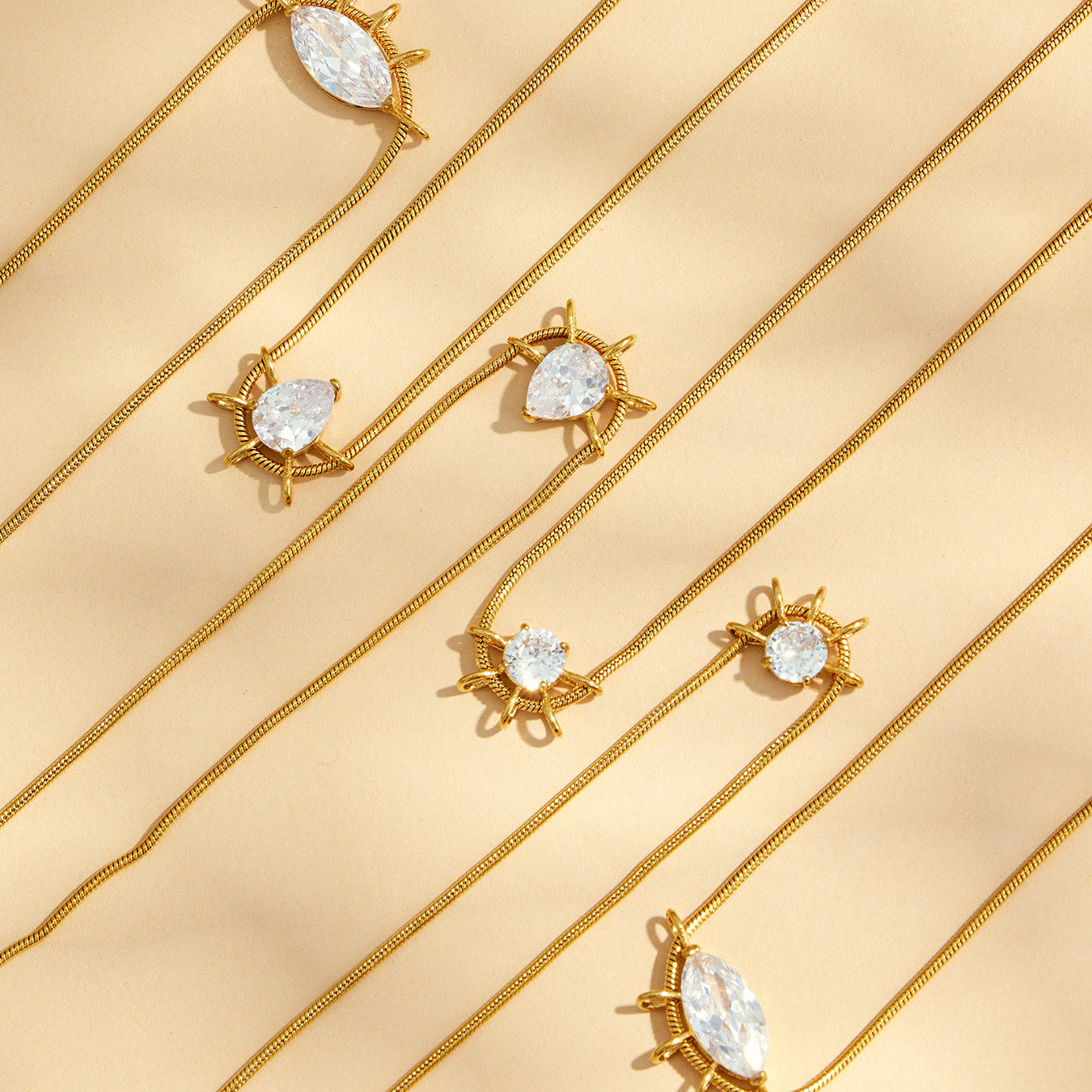 Assorted geometric zircon pendant necklaces arranged diagonally on a beige background