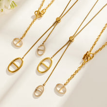 Geometric zircon toggle and lariat necklaces displayed in gold-tone stainless steel