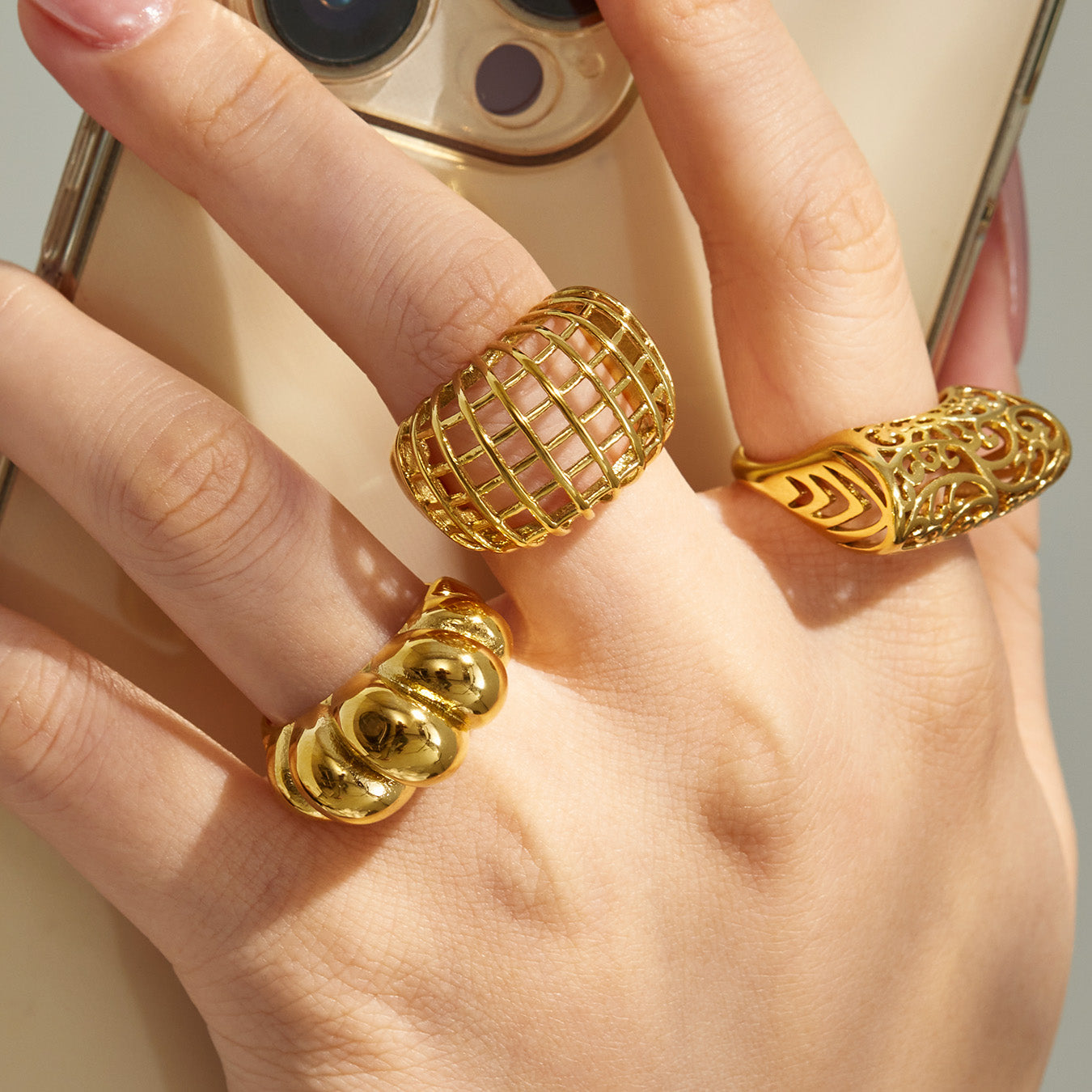 Model wearing multiple gold tone 316L stainless steel statement rings in hollow and geometric designs