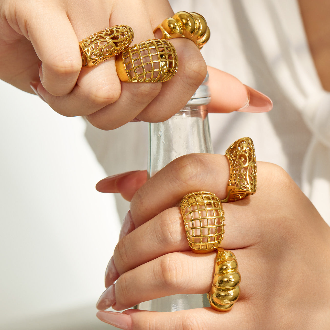 Model wearing gold tone 316L stainless steel sculptural statement rings on multiple fingers