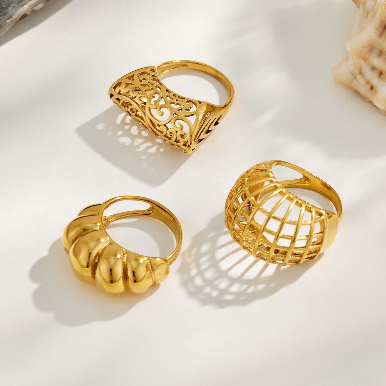 Three gold tone 316L stainless steel rings in sculptural hollow and cage statement designs