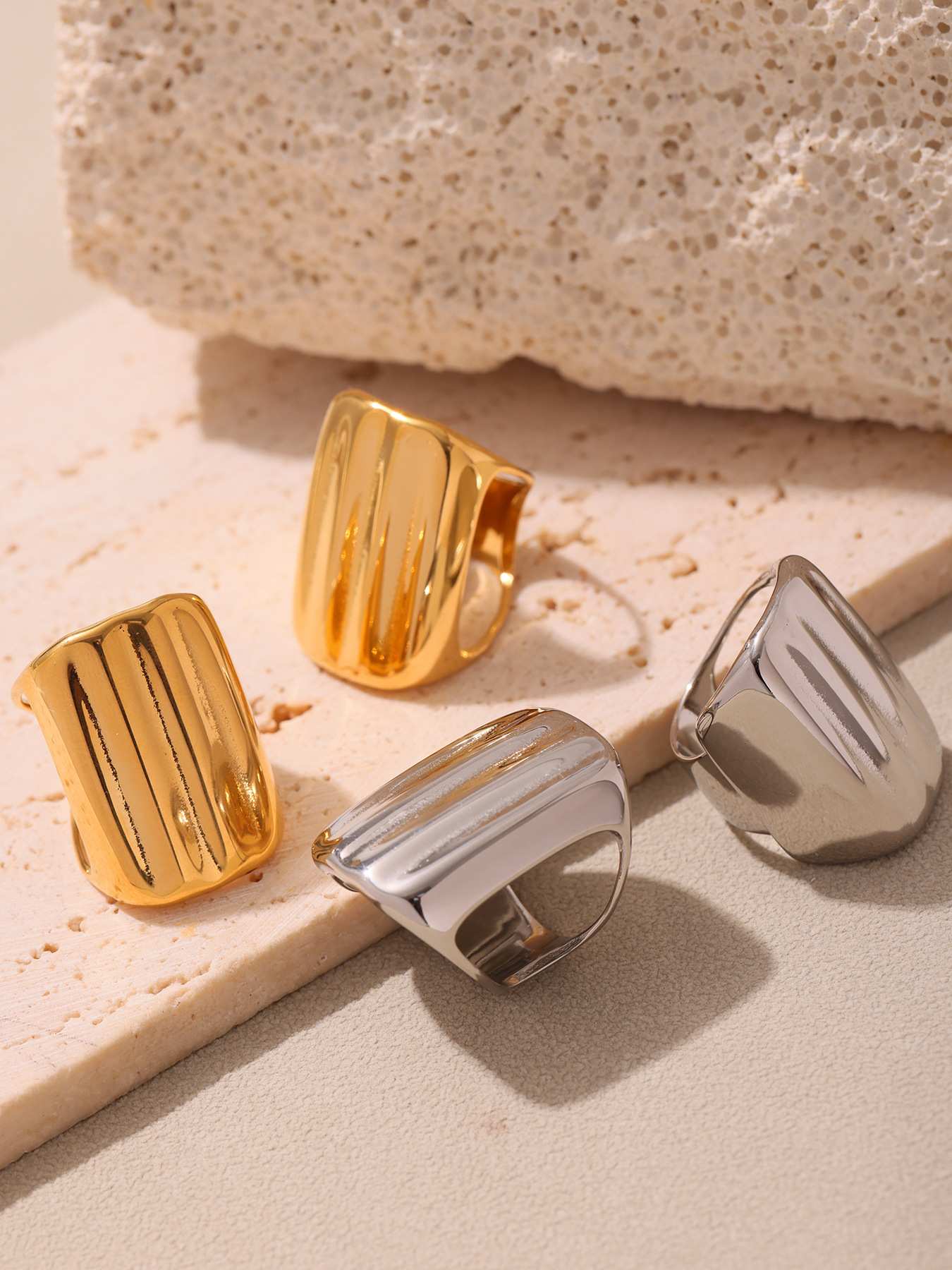 Gold and steel tone geometric wide band rings displayed on stone for wholesale buyers