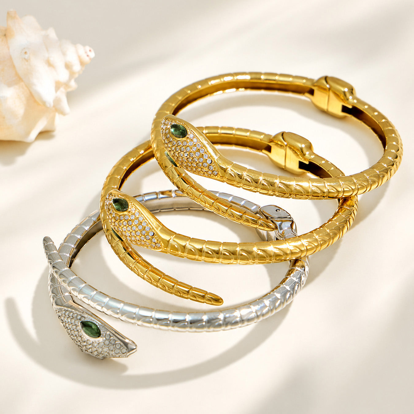 Gold and polished steel snake open bangles arranged together on a light background