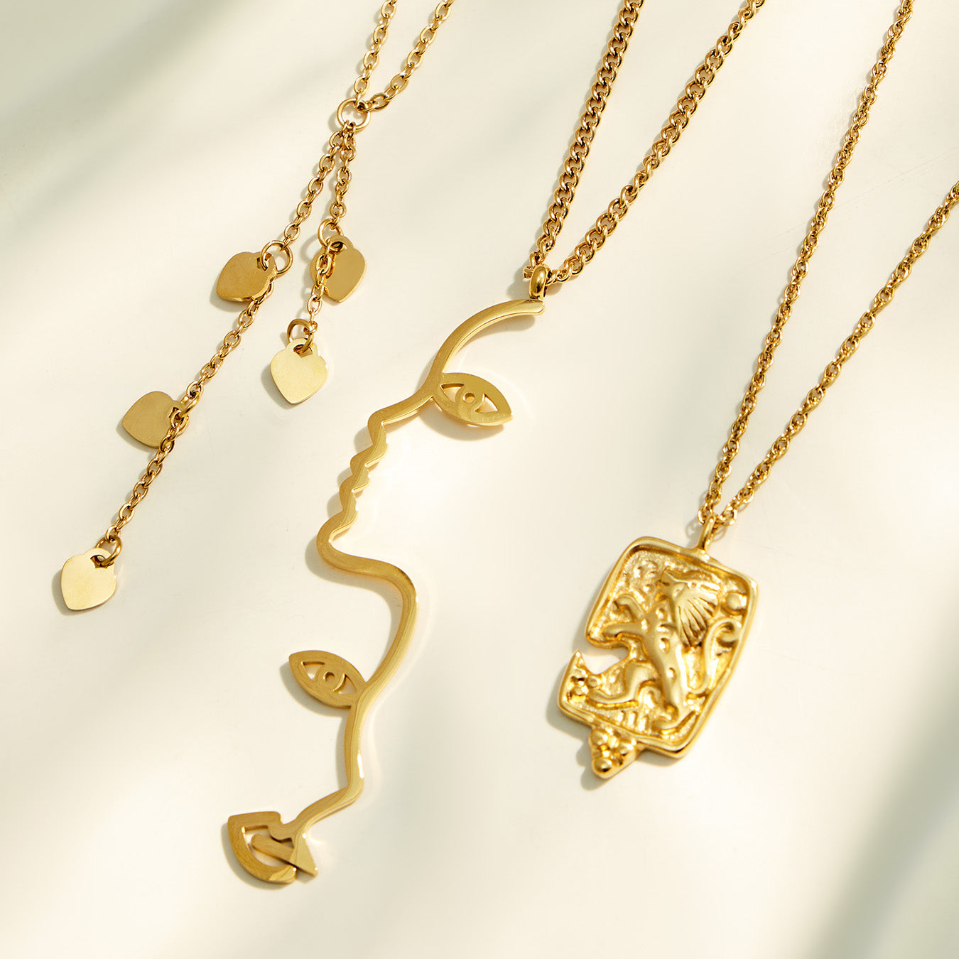 Gold artistic pendant necklaces featuring heart, textured rectangle and abstract face designs