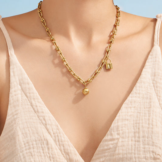 Model wearing a gold ball lock chain link necklace with a white V-neck outfit