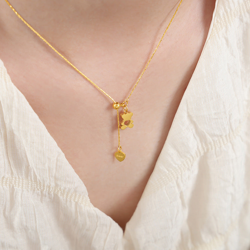 Model wearing a gold bear pendant necklace with a heart charm and minimalist stainless steel chain